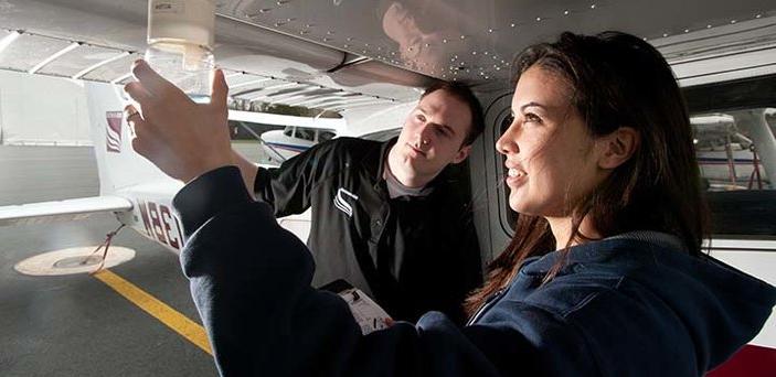 一名飞行教官在飞机外与一名航空学生一起工作