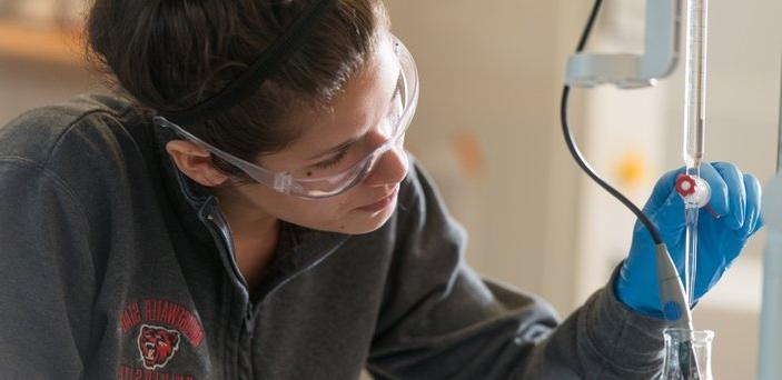 一名学生在使用化学实验室设备时戴着橡胶手套和安全眼镜